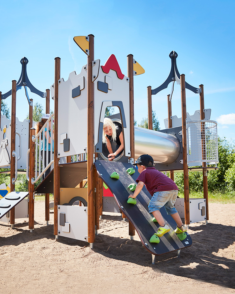 Children play at a small playground unit with a slide.